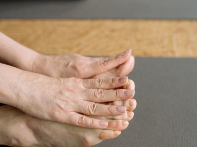 Close up of hands reaching for toes in stretch.